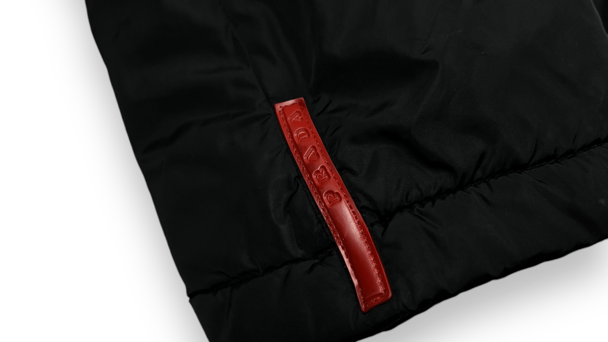 Logo Prada en gros plan sur une parka noire authentifiée chez NB08, repère d'authentification