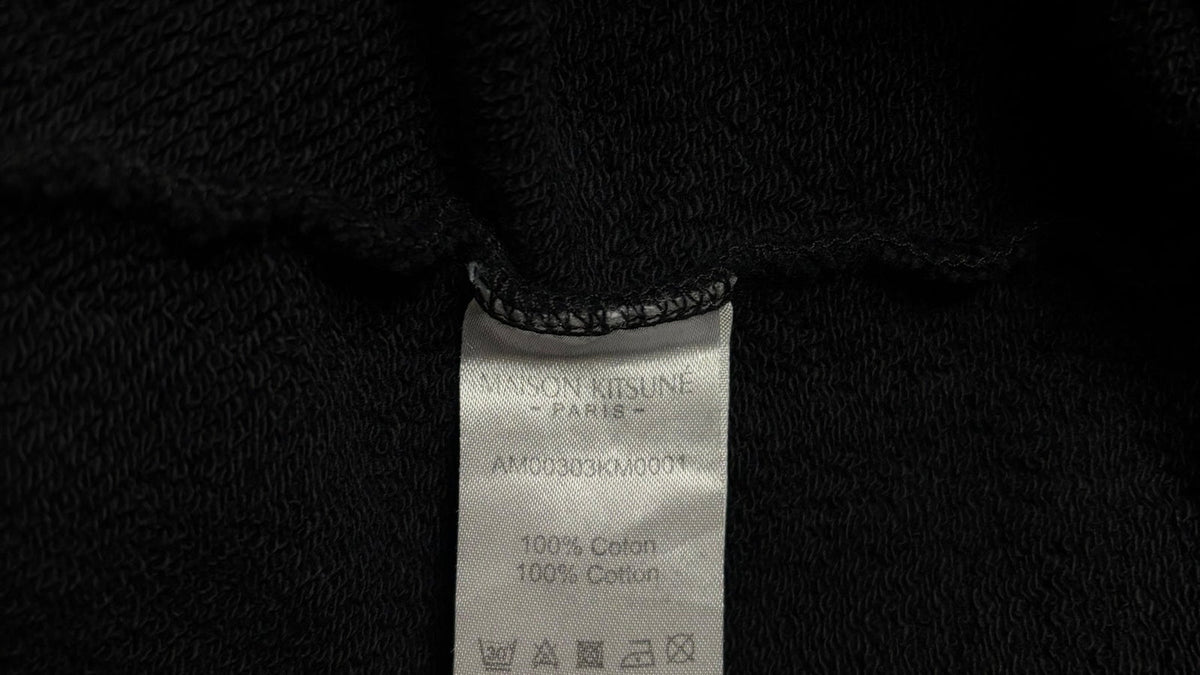 Logo Maison Kitsuné en gros plan sur un pull noir authentifié chez NB08
