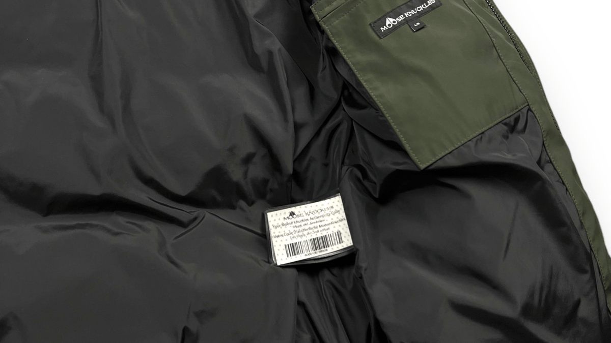 Logo Moose Knuckles en gros plan sur une parka kaki authentifiée chez NB08