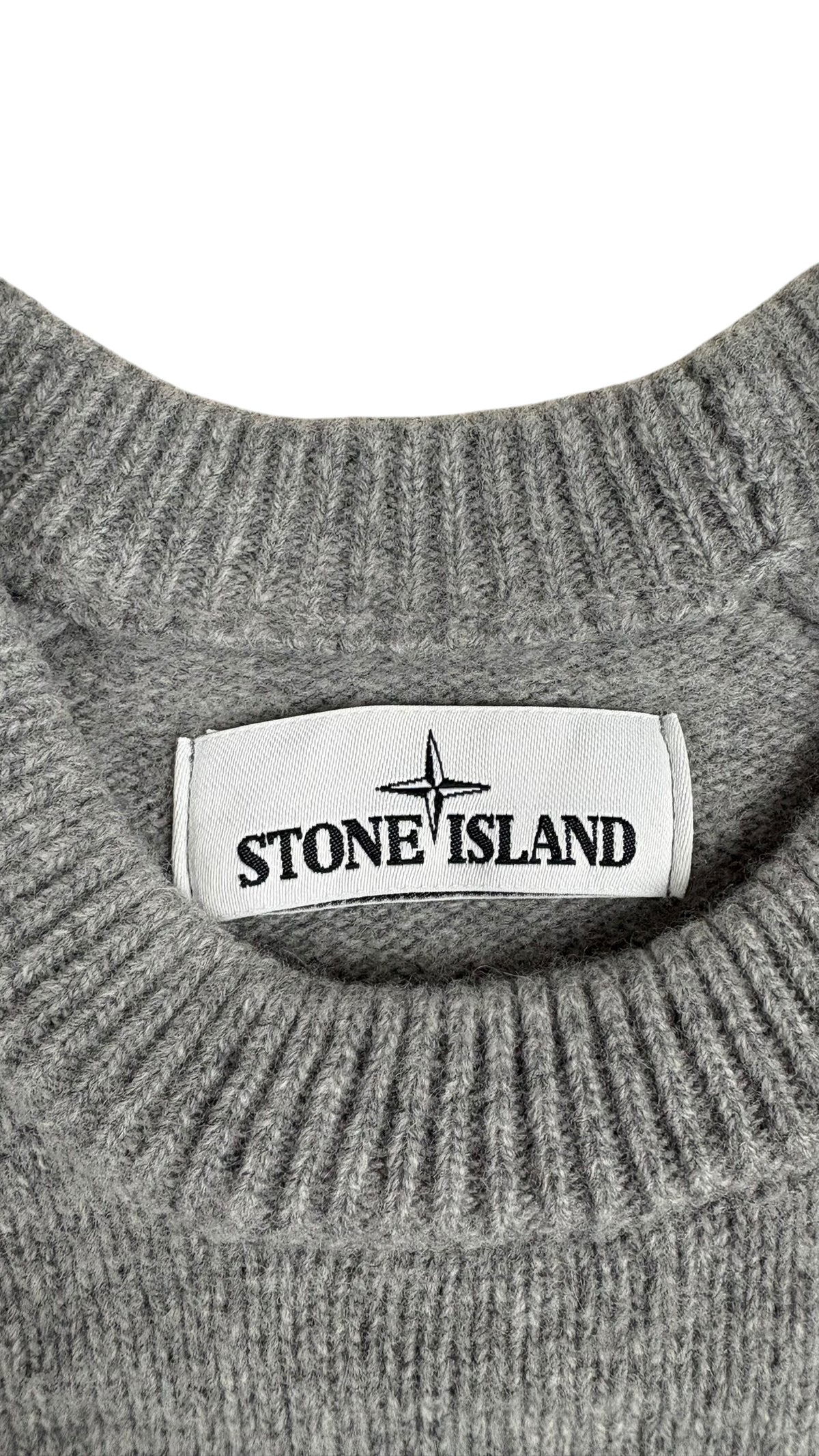 Étiquette de marque Stone Island cousue sur le col côtelé gris du pull