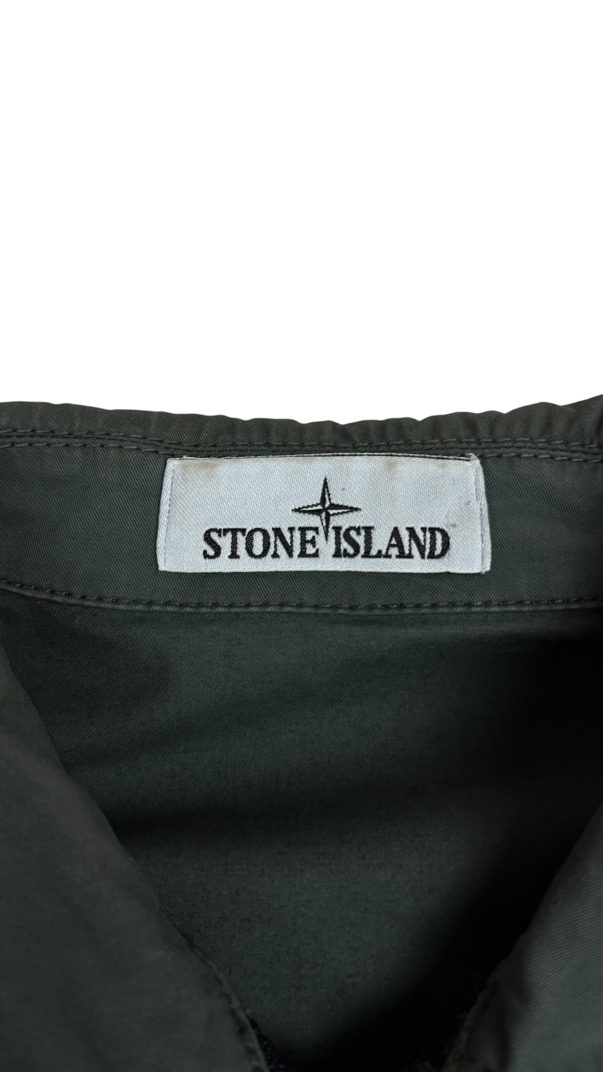 Gros plan sur l'écusson boussole Stone Island cousu sur la manche de la surchemise kaki, autre angle, vue détail